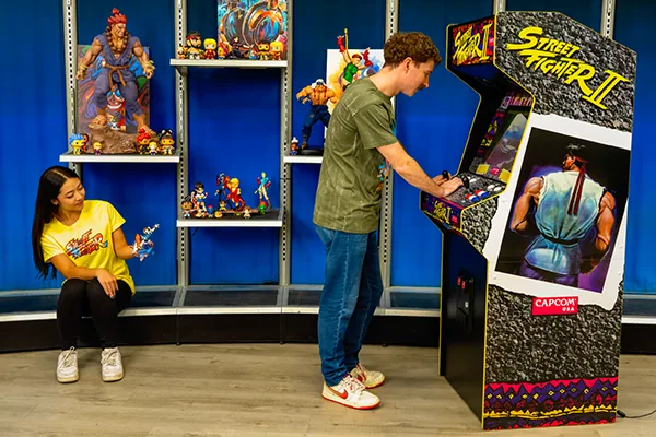 Playing the Street Fighter II XT in a game room full of figures
